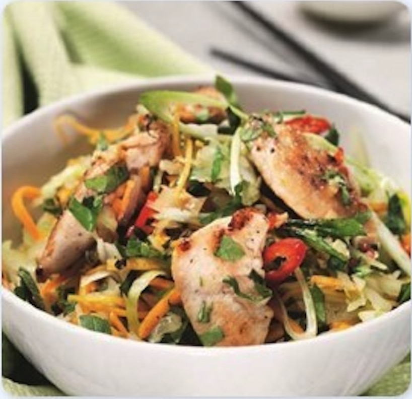 Bowl of healthy salad with grilled chicken strips, nuts, and seeds